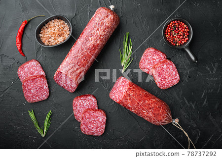 Traditional smoked salami sausage with spices, on black dark stone table background, top view flat lay Traditional smoked salami sausage with spices, on black dark stone table background, top view flat lay 78737292