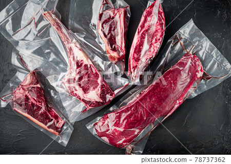 Beef steak vacuum, tomahawk, t bone, club steak, rib eye and tenderloin cuts, on black stone background, top view flat lay Beef steak vacuum, tomahawk, t bone, club steak, rib eye and tenderloin cuts, on black stone background, top view flat lay 78737362