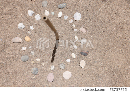 Sundial is lined with stones on sand of sea beach closeup background 78737755