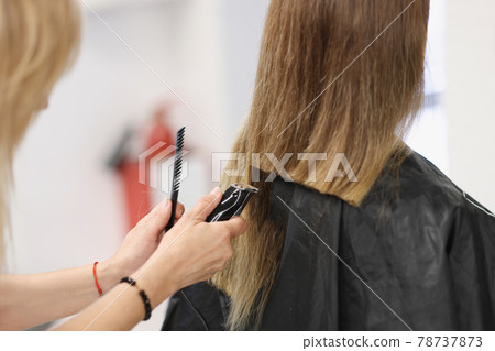 Hairdresser doing hair cutting of woman using clipper in salon closeup Hairdresser doing hair cutting of woman using clipper in salon closeup 78737873