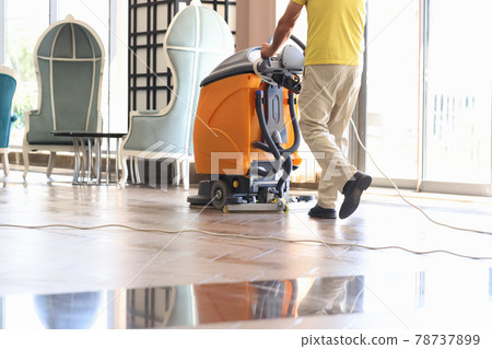 Janitor is cleaning hall with washing vacuum cleaner closeup 78737899