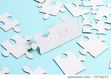 Close-Up White Jigsaw Pattern Puzzle Pieces To Be Connected With Missing Last Piece Positioned On A Flat Lay Background With Different Texture And Paper Supplies Accesories Close-Up White Jigsaw Pattern Puzzle Pieces To Be Connected With Missing Last Piece Positioned On A Flat Lay Background With Different Texture And Paper Supplies Accesories 78738253