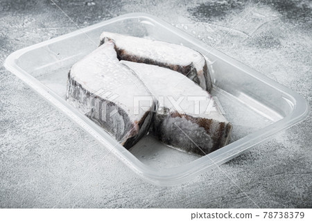 Frozen Greenland halibut steaks vacuum pack, on gray stone table background, with copy space for text 78738379