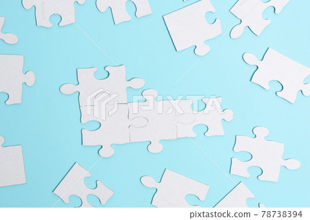 Close-Up White Jigsaw Pattern Puzzle Pieces To Be Connected With Missing Last Piece Positioned On A Flat Lay Background With Different Texture And Paper Supplies Accesories 78738394