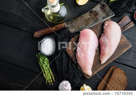 Crumbed uncooked chicken breast ingredient with butcher knife on black wooden table, flat lay with space for text 78738395