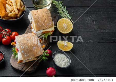 Fish fingers sandwich , on wooden cutting board, on black wooden table background , with copyspace and space for text 78738404