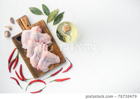 Uncooked chicken wings with spices, on wooden cutting board, on white background, top view flat lay, with copy space for text 78738479