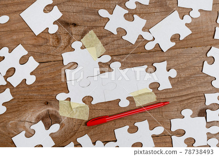 Close-Up White Jigsaw Pattern Puzzle Pieces To Be Connected With Missing Last Piece Positioned On A Flat Lay Background With Different Texture And Paper Supplies Accesories 78738493