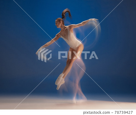 Graceful young beautiful girl, female ballet dancer dancing isolated over blue background. Reflection effect 78739427