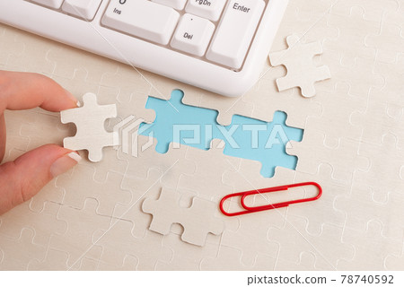 Close-Up White Jigsaw Pattern Puzzle Pieces To Be Connected With Missing Last Piece Positioned On A Flat Lay Background With Different Texture And Paper Supplies Accesories Close-Up White Jigsaw Pattern Puzzle Pieces To Be Connected With Missing Last Piece Positioned On A Flat Lay Background With Different Texture And Paper Supplies Accesories 78740592