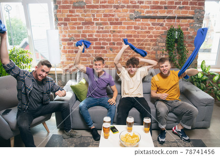 High angle view of young people watching TV, sport match together. Concept of friendship, leisure activity, emotions High angle view of young people watching TV, sport match together. Concept of friendship, leisure activity, emotions 78741456