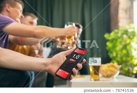 Bet for winner. Young men watching TV, sport match together. Concept of friendship, leisure activity, emotions Bet for winner. Young men watching TV, sport match together. Concept of friendship, leisure activity, emotions 78741526