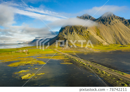 View from flying drone. Stunning scene of Stokksnes cape with Vestrahorn on background. Panoramic Icelandic view of black sand dunes by tide with yellow grass View from flying drone. Stunning scene of Stokksnes cape with Vestrahorn on background. Panoramic Icelandic view of black sand dunes by tide with yellow grass 78742211