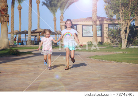 Happy sisters run on footpath in tropical resort Happy sisters run on footpath in tropical resort 78742403