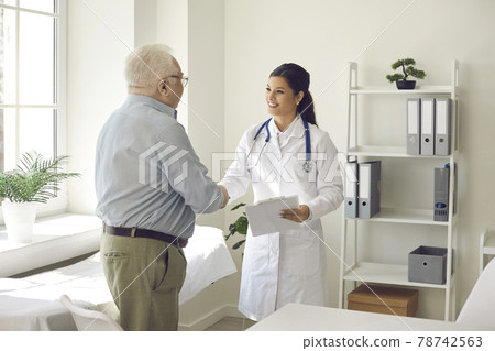 Male elderly patient and woman physician handshaking at modern clinic office 78742563