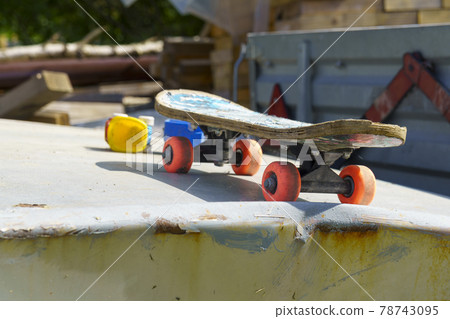 Old shabby kids skateboard on the hood of old car outdoors Old shabby kids skateboard on the hood of old car outdoors 78743095