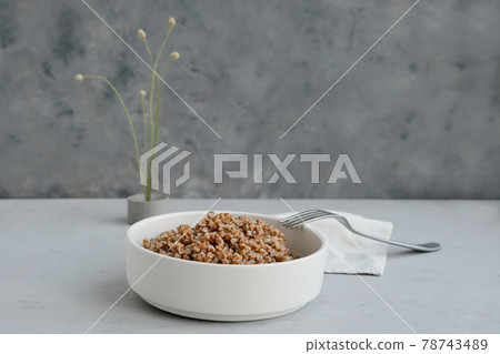 Bowl of buckwheat on a grey concrete background in minimalistic style. Concept of healthy food.  78743489
