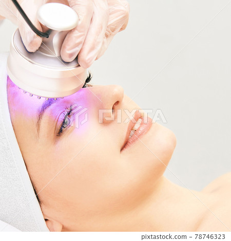 Light infrared therapy. Cosmetology head procedure. Beauty woman face. Cosmetic salon device. Facial skin rejuvenation Light infrared therapy. Cosmetology head procedure. Beauty woman face. Cosmetic salon device. Facial skin rejuvenation 78746323