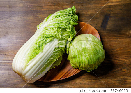 head of Peking cabbage and lettuce on a wooden cutting board on the table. head of Peking cabbage and lettuce on a wooden cutting board on the table. 78746623