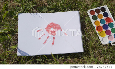 The child leaves a trail of paint with his palm. 78747345