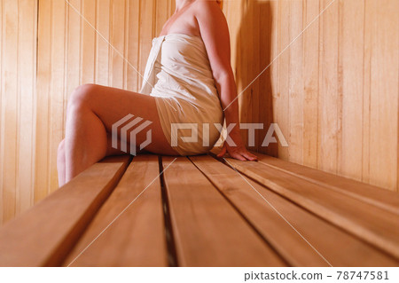 Traditional old Russian bathhouse SPA Concept. Woman in towel relaxing in traditional Finnish sauna interior steam room. Relax country village bath concept. Traditional old Russian bathhouse SPA Concept. Woman in towel relaxing in traditional Finnish sauna interior steam room. Relax country village bath concept. 78747581