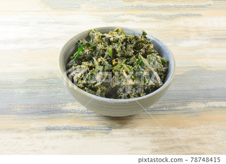 Organic dehydrated kale chips coated with dried tahini in ceramic snack bowl on table Organic dehydrated kale chips coated with dried tahini in ceramic snack bowl on table 78748415