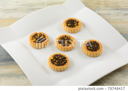 Citrus tartlet cookies with cocoa and orange sprinkles on top on white dessert plate Citrus tartlet cookies with cocoa and orange sprinkles on top on white dessert plate 78748417