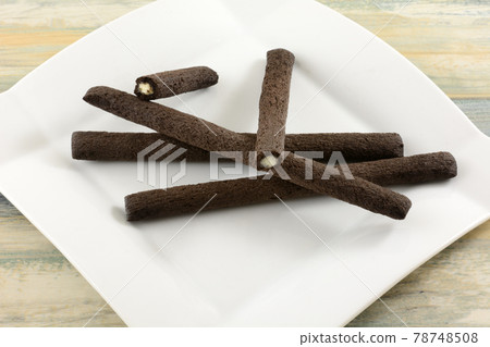 Chocolate cereal sticks filled with sweet milk cream on white snack plate 78748508