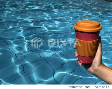 Woman enjoying coffee in a reusable bamboo mug at the swimming pool Woman enjoying coffee in a reusable bamboo mug at the swimming pool 78748513