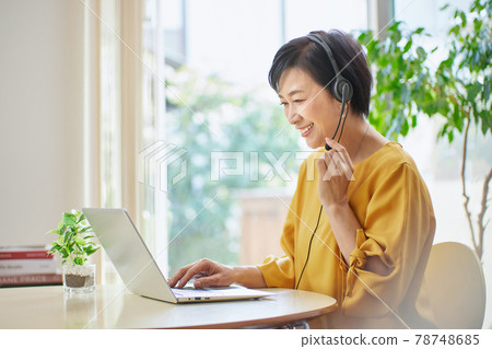Middle woman having an online meeting in the living room Middle woman having an online meeting in the living room 78748685