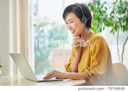 Middle woman having an online meeting in the living room Middle woman having an online meeting in the living room 78748686