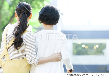 Back view of a female caregiver assisting senior women in walking 78751512