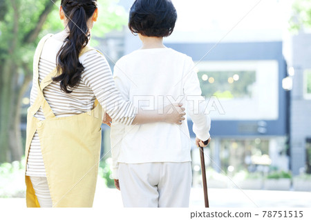 Back view of a female caregiver assisting senior women in walking Back view of a female caregiver assisting senior women in walking 78751515