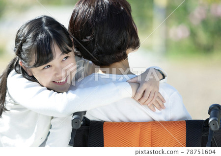 Granddaughter hugging grandmother sitting in a wheelchair Granddaughter hugging grandmother sitting in a wheelchair 78751604
