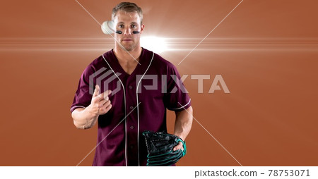 Caucasian male baseball pitcher tossing a ball in the air against spot of light on orange background 78753071
