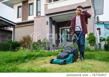 tired man using lawn mower cutting grass at home 78756907