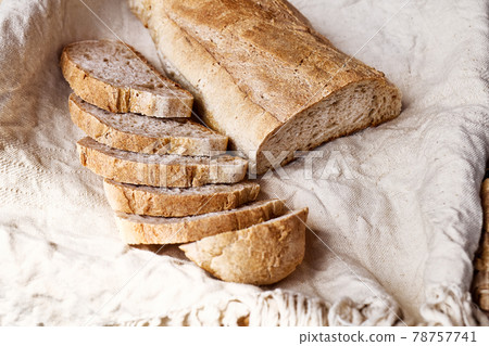 Sliced bread on linen towel. Top view of sourdough bread. Traditional leavened bread baking method. Healthy food concept 78757741