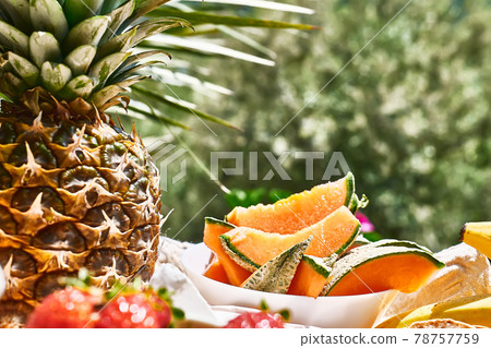 Honey melon sliced and pineapple on the table in the garden. Summer Italian Breakfast or picnic. Selective focus. Honey melon sliced and pineapple on the table in the garden. Summer Italian Breakfast or picnic. Selective focus. 78757759