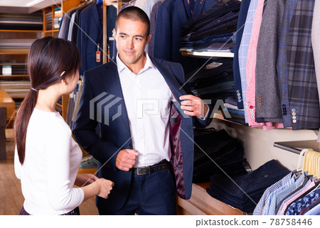 Smiling couple examining various suits in mens cloths store 78758446