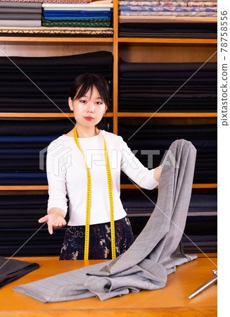 Friendly chinese woman tailor at work desk in clothing store Friendly chinese woman tailor at work desk in clothing store 78758556