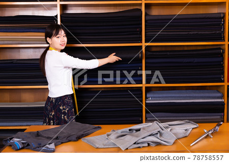 Friendly chinese woman tailor at work desk in clothing store Friendly chinese woman tailor at work desk in clothing store 78758557