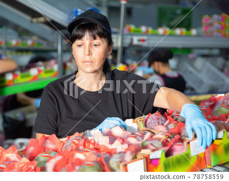 Confident female working with mango at sorting department at fruits packing facility Confident female working with mango at sorting department at fruits packing facility 78758559