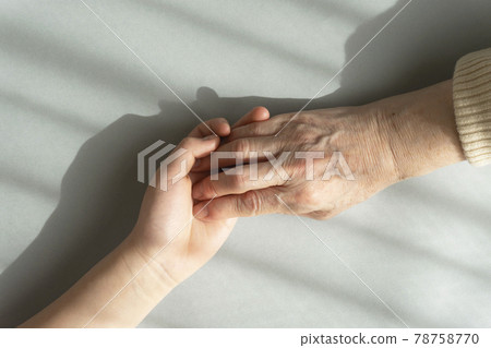 Grandmother's hand grabbing the hand of her beloved grandmother under the light through the curtain 78758770