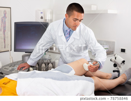 Positive male doctor diagnosing female patient using modern ultrasound scanner in private clinic Positive male doctor diagnosing female patient using modern ultrasound scanner in private clinic 78758846