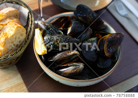 Delicious steamed in green sauce mussels, served at plate at table 78758888