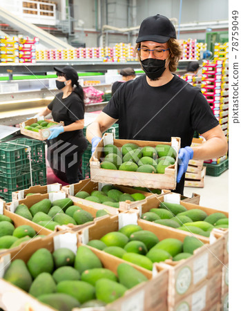 Ordinary man in mask with crate of fresh avocado 78759049