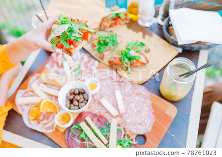 Fresh bruschettes, cheeses and meat on the board in outdoor cafe with amazing view in Manarola Fresh bruschettes, cheeses and meat on the board in outdoor cafe with amazing view in Manarola 78761023