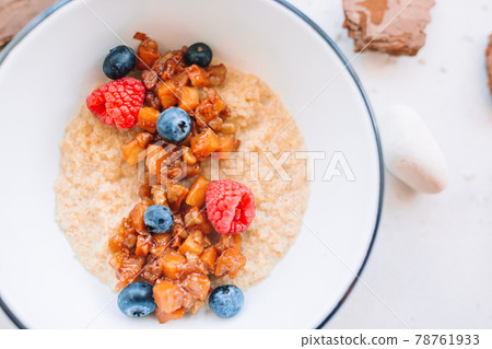 Oatmeal porridge in bowl topped with fresh blueberries, cranberries and homemade crunchy granola Oatmeal porridge in bowl topped with fresh blueberries, cranberries and homemade crunchy granola 78761933