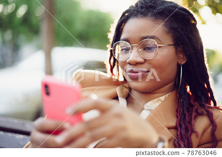 African american woman standing in a street and using smartphone African american woman standing in a street and using smartphone 78763046