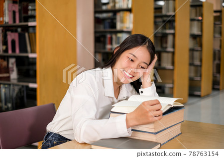 Young Asian women are searching for books and reading from the bookshelves in the college library to research and develop themselves in education Young Asian women are searching for books and reading from the bookshelves in the college library to research and develop themselves in education 78763154